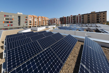 Pannelli fotovoltaici sopra il tetto di un palazzo, intorno altri palazzi - obrazy, fototapety, plakaty