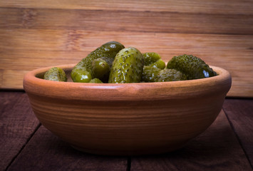 Pickles in a clay bowl on a dark rustic background, side view