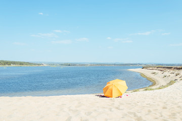 Orange umbrella on beach by the sea on a sunny day.