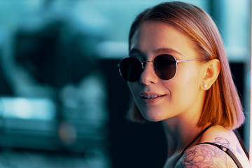 Fashion portrait of young attractive girl in sunglasses. Neon light