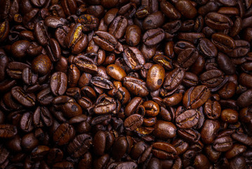 Fototapeta premium Close up to a heap of coffee beans. Macro photography of fresh roasted coffee beans high resolution. Detailed macro picture on roasted coffee beans. Close-up of brown coffee beans background image