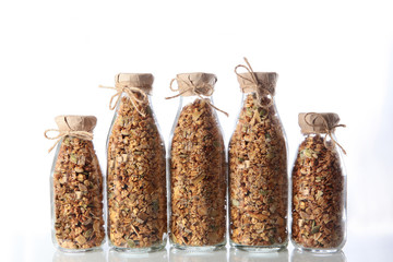 Many glass bottles with granola or muesli on a white background. An isolated object. Copy of the...