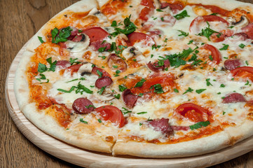 pizza on a wooden tray stands on a wooden table