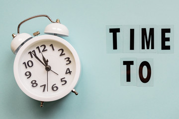 Business concept. time management. White alarm clock and text Time to on blue background.