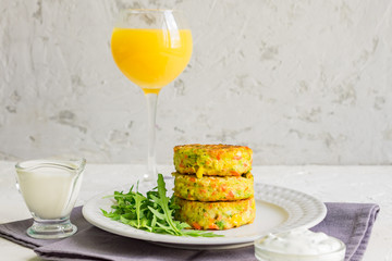 Vegan vegetable burgers with arugula salad and sauce served in a white plate and orange juice, copy space