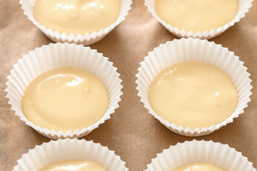 Cupcake dough in paper molds. Sweets prepared for baking.