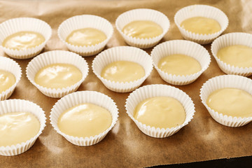 Cupcake dough in paper molds. Sweets prepared for baking.