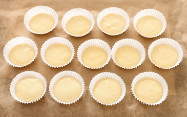 Cupcake dough in paper molds. Sweets prepared for baking.