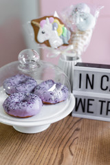 Delicious sweet donuts with purple icing lie on a white plate. Unhealthy and tasty food