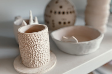 Raw ceramic pottery kitchenware drying on the shelf. Art workshop concept