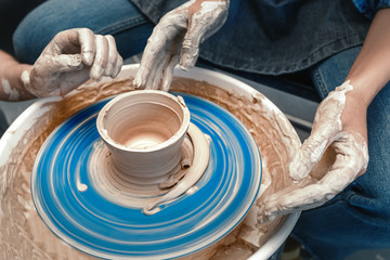 Close-up of female hands sculpting clay on a Potter's wheel. Concept of hobby and cretivity at home and in the Studio workshop