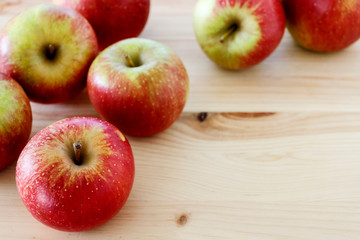 Red and yellow apples on wooden table.
