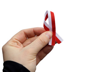Hand with red and white ribbon on white background, isolated. Flag background national holiday country november celebration.1 of May, flag or independence or labor day. Government holiday in poland