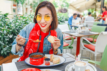 Asian girl eats soup on an outdoor terrace in a restaurant. Fast food cafe concept