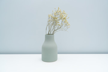 Place the vase with dried flowers on the white table