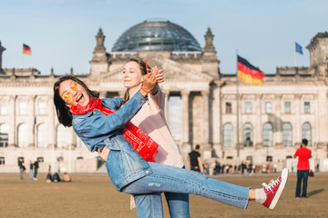 Two girls friends - students or tourists have fun and have a good time on the lawn near the...