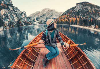 Happy and fearless Asian traveler sails in a boat on a beautiful high mountain lake at autumn time