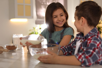 Obraz na płótnie Canvas Cute little children cooking dough in kitchen at home