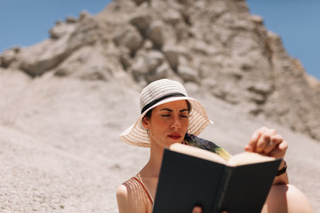 Woman reading a book wearing dress seating in the desert