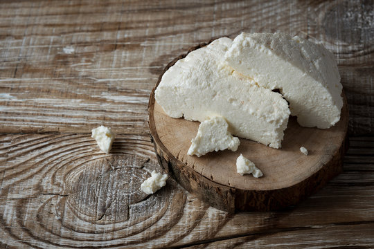 homemade Adyghe cheese cut into pieces on a wooden background