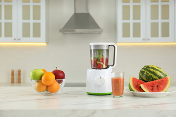 Blender and smoothie ingredients on table in kitchen