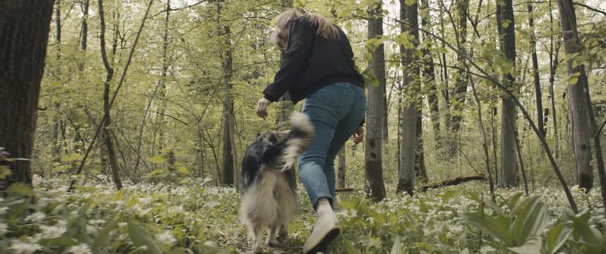 Woman runs free with her cute female dog smiling on a forest trail in nature park on a post coronavirus staycation travel