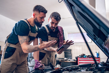 Two mechanics working on reports in a workshop