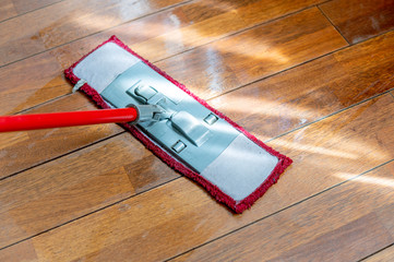 A mop washing a wooden floor in an apartment. Concept of care for the cleanliness of the apartment. Mopping the floor