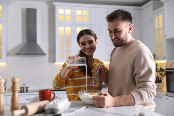 Lovely young couple cooking dough together in kitchen