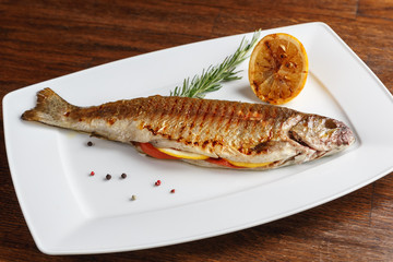 Grilled trout with resemary and lemon served on a white plate