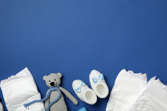 Diapers and baby accessories on blue background, flat lay. Space for text