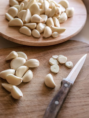 Fototapeta na wymiar one cut and many uncut peeled cloves of garlic on wooden cutting boards, knife