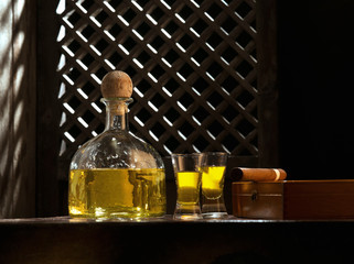 Close up view of bottle of tequila anejo and cigar on color background