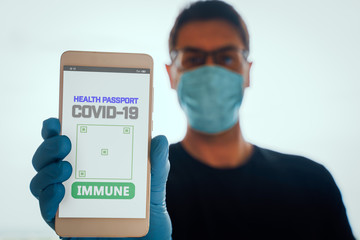 Man holding a smartphone with Immune digital passport for covid-19. Suitable for immunity passport app on the phone to monitorize the population movements at the end of the lockdown