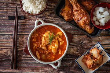 Korean food on wooden background, kimchi soup and fried chicken with source, garlic, spicy and steamed rice