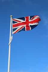 The national flag of the United Kingdom flying against a blue sky. Union Jack