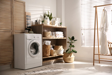 Modern washing machine and shelving unit in laundry room interior