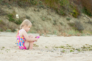 C hild playing with sand at the beach in summer.