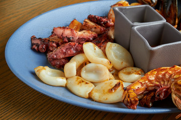 Plate with deep-fried seafood - mussels, octopuses, scallops, squid and shrimp. Antipasto. CLose up view. Wooden background