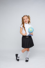 a little girl in school uniform  holds a globe in her hands on a white background