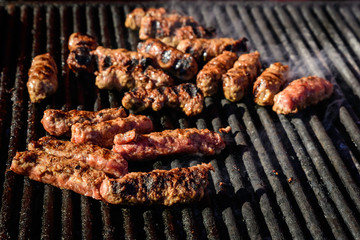 Grilled meat rolls called Mici or Mititei, traditional fresh Romanian barbeque grill food cooked on the barbeque at a street food market
