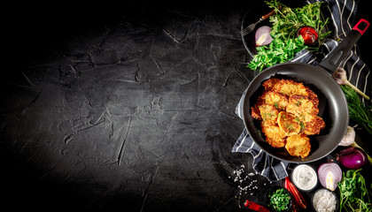Potato pancakes with sour cream, herbs, garlic and spices on a dark background. Top view with copy space