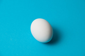 One white egg on a blue background. The concept of calorie content, life, healthy nutrition, Easter