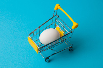 Egg in a yellow grocery cart on a blue background