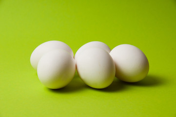 Several chicken eggs on bright green background, copy space