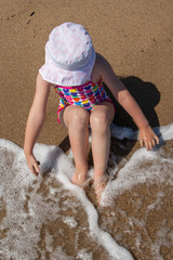 Girl in a Panama hat sit on the beach.