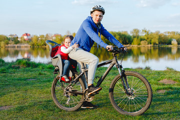 Cheerful family biking in park. father with daughter on a bicycle