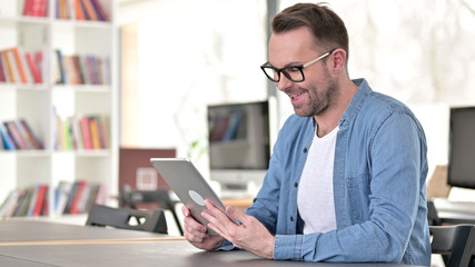 Video Chat on Tablet by Young Man in Glasses