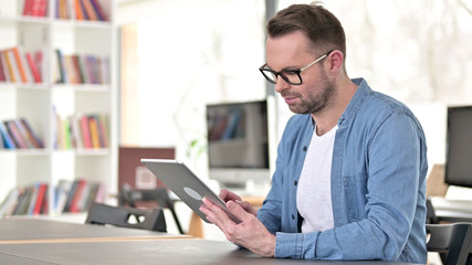 Young Man in Glasses Using Tablet at Work