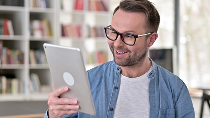 Video Chat on Tablet by Young Man in Glasses
